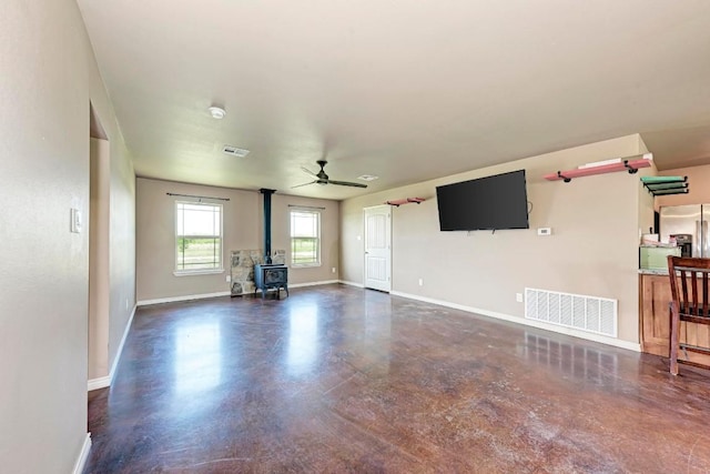 unfurnished living room featuring a wood stove and ceiling fan