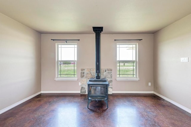 unfurnished living room featuring a wood stove and a healthy amount of sunlight