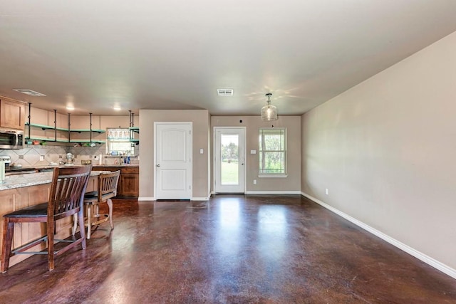 kitchen featuring decorative backsplash, appliances with stainless steel finishes, and a kitchen bar