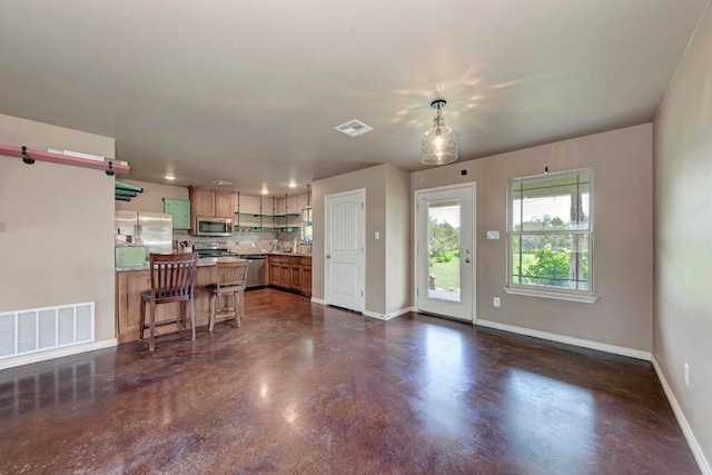 kitchen featuring a breakfast bar area, decorative backsplash, decorative light fixtures, and appliances with stainless steel finishes