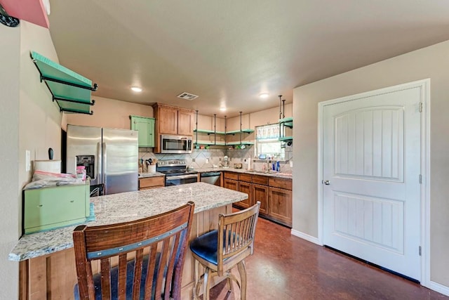 kitchen featuring kitchen peninsula, backsplash, stainless steel appliances, sink, and a breakfast bar area