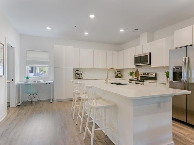 kitchen featuring sink, an island with sink, white cabinets, and appliances with stainless steel finishes