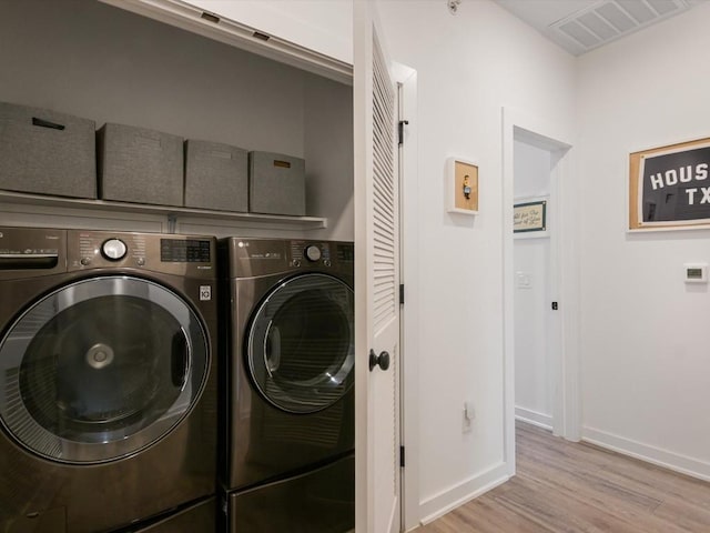 clothes washing area featuring light wood-type flooring and washer and clothes dryer