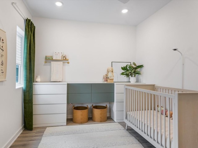 bedroom featuring a crib and light hardwood / wood-style flooring