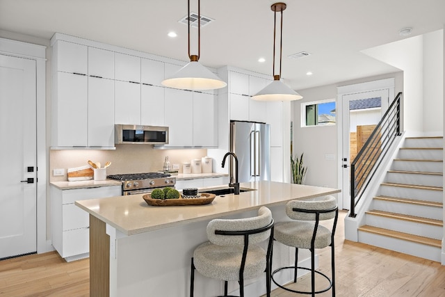 kitchen with pendant lighting, sink, an island with sink, and appliances with stainless steel finishes