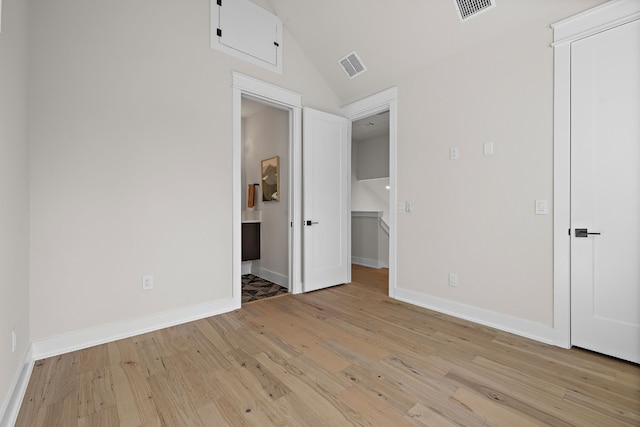 unfurnished bedroom featuring light wood-type flooring, visible vents, vaulted ceiling, and baseboards