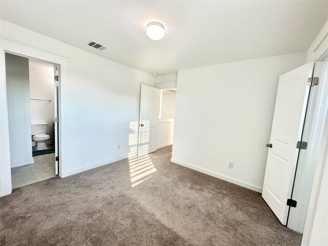 unfurnished bedroom featuring ensuite bathroom and carpet floors