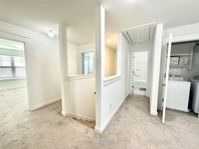 hallway featuring washer and dryer and light carpet