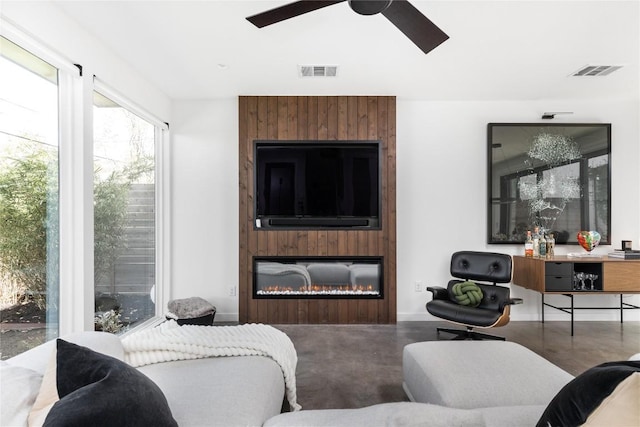 living room with ceiling fan, a large fireplace, and concrete floors