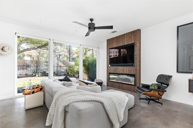 living room featuring a fireplace, ceiling fan, plenty of natural light, and concrete floors