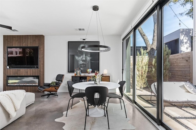 dining space featuring a fireplace, concrete flooring, and an inviting chandelier