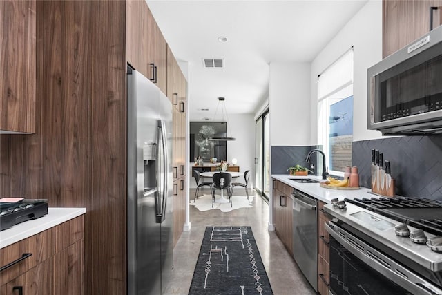 kitchen with decorative backsplash, pendant lighting, stainless steel appliances, and sink