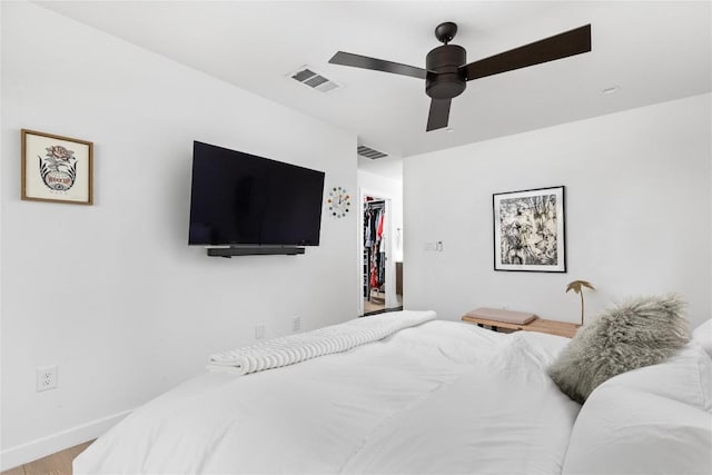 bedroom with a closet, a spacious closet, ceiling fan, and hardwood / wood-style flooring