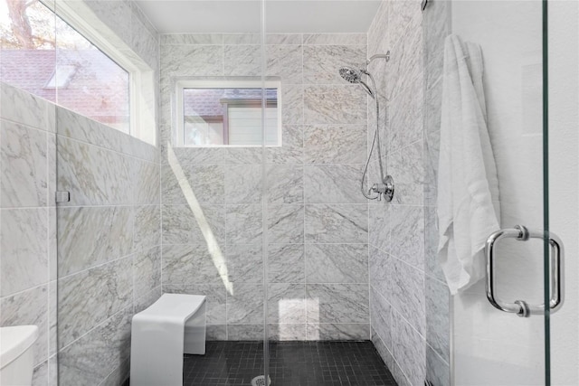 bathroom featuring a shower with door and toilet