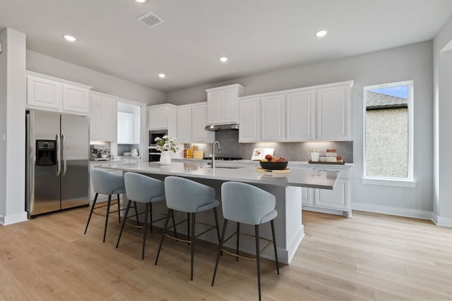kitchen with white cabinets, a sink, visible vents, backsplash, and appliances with stainless steel finishes