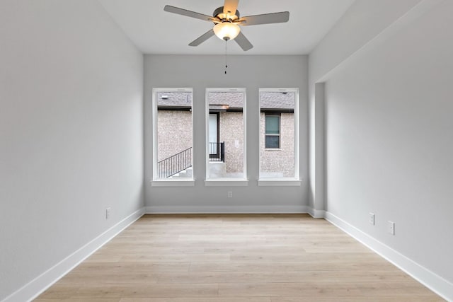empty room with a ceiling fan, baseboards, and light wood-style floors