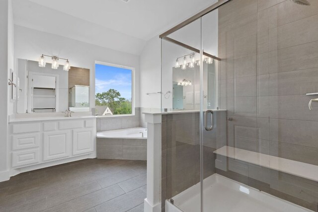 bathroom with vaulted ceiling, a shower stall, a garden tub, and vanity