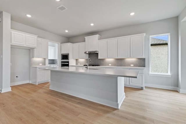 kitchen featuring stainless steel appliances, light countertops, visible vents, a sink, and decorative backsplash
