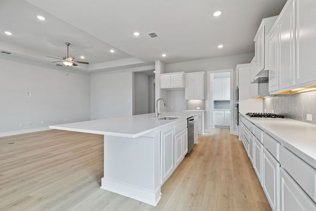 kitchen with light wood-style flooring, a sink, visible vents, decorative backsplash, and ceiling fan