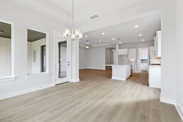 unfurnished living room featuring baseboards, light wood-style floors, visible vents, and a sink