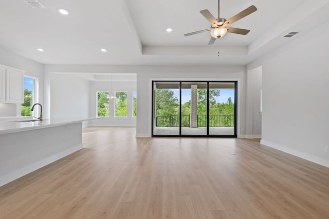 unfurnished living room with plenty of natural light, a ceiling fan, baseboards, and light wood-style flooring