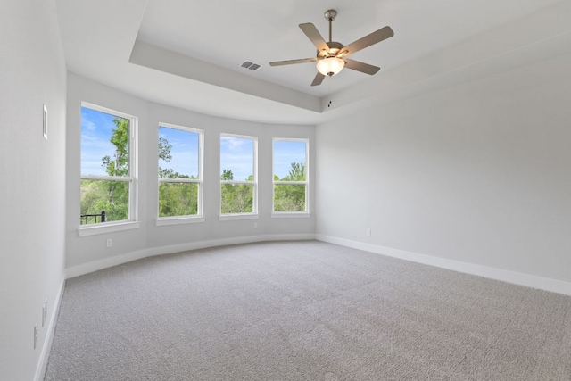 unfurnished room featuring carpet, a raised ceiling, visible vents, a ceiling fan, and baseboards
