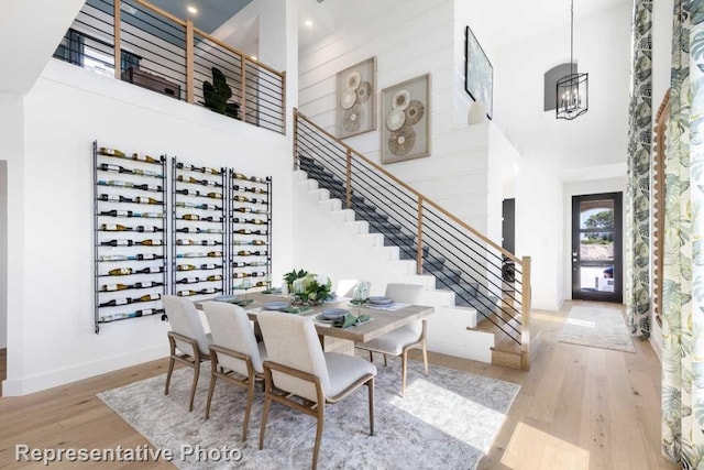 dining space featuring hardwood / wood-style floors, a notable chandelier, and a high ceiling