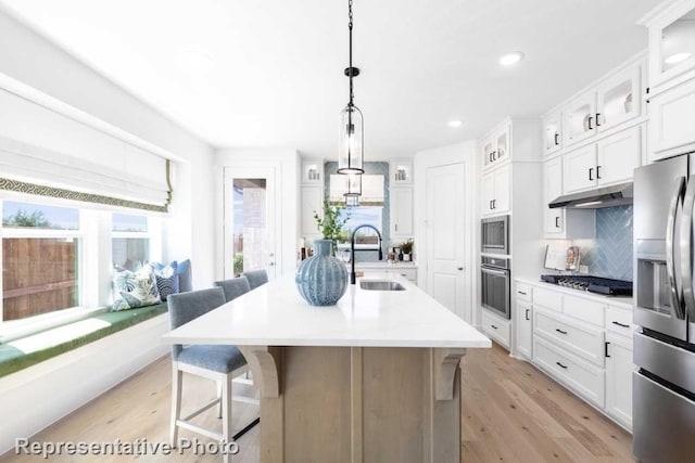 kitchen with a kitchen island with sink, sink, white cabinets, and appliances with stainless steel finishes