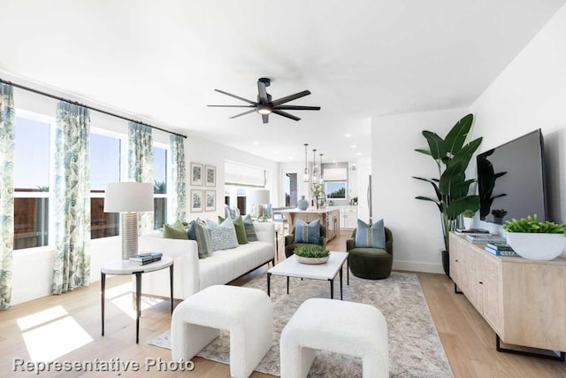 living room featuring ceiling fan with notable chandelier and light hardwood / wood-style floors