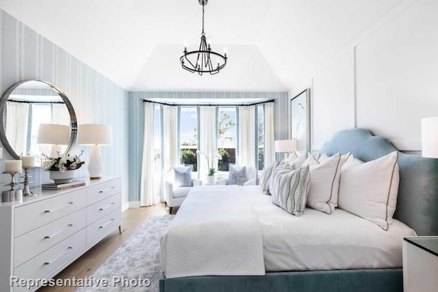 bedroom featuring multiple windows, a chandelier, lofted ceiling, and light wood-type flooring