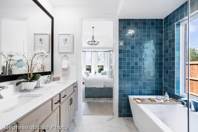 bathroom with vanity, an inviting chandelier, plenty of natural light, and a tub