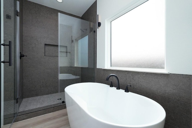 bathroom featuring hardwood / wood-style floors, shower with separate bathtub, and tile walls