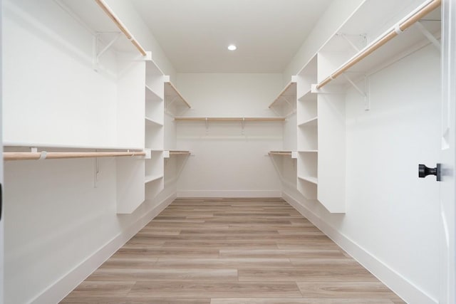 walk in closet with light hardwood / wood-style flooring