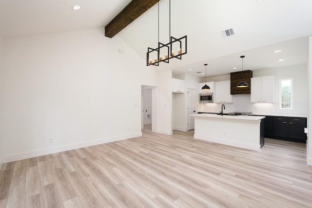 kitchen with light hardwood / wood-style flooring, white cabinetry, and a kitchen island with sink