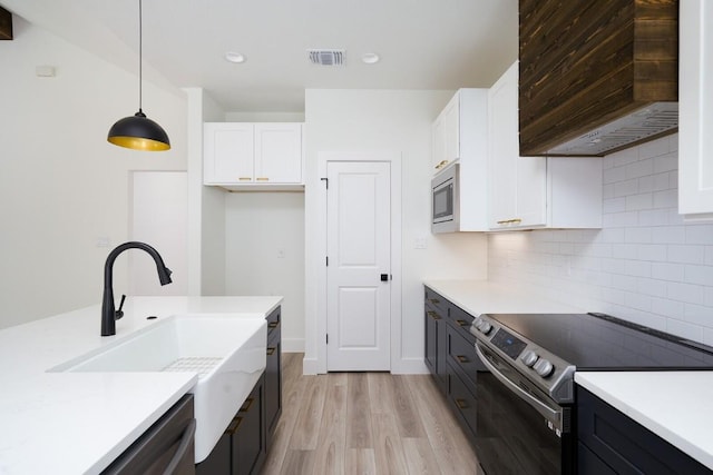 kitchen featuring white cabinets, hanging light fixtures, light wood-type flooring, and appliances with stainless steel finishes