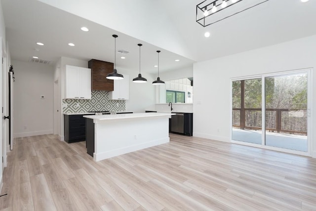 kitchen with decorative light fixtures, a center island, light wood-type flooring, and white cabinetry