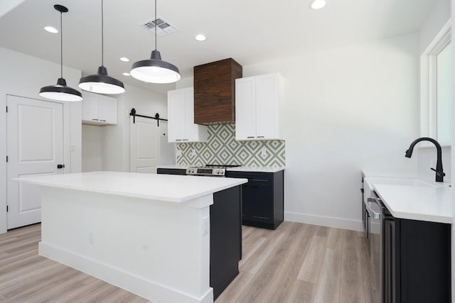 kitchen featuring white cabinets, light wood-type flooring, a barn door, and a center island