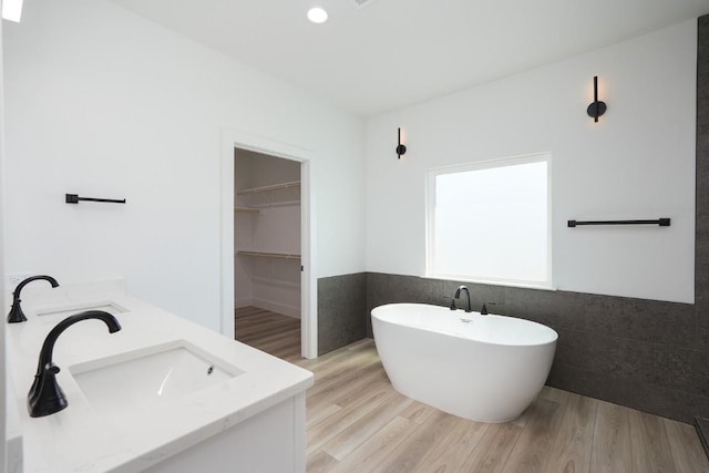 bathroom featuring hardwood / wood-style floors, a bathtub, tile walls, and vanity