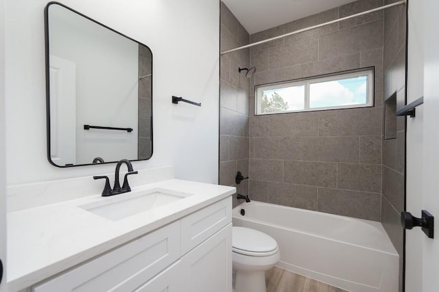 full bathroom featuring hardwood / wood-style flooring, vanity, toilet, and tiled shower / bath