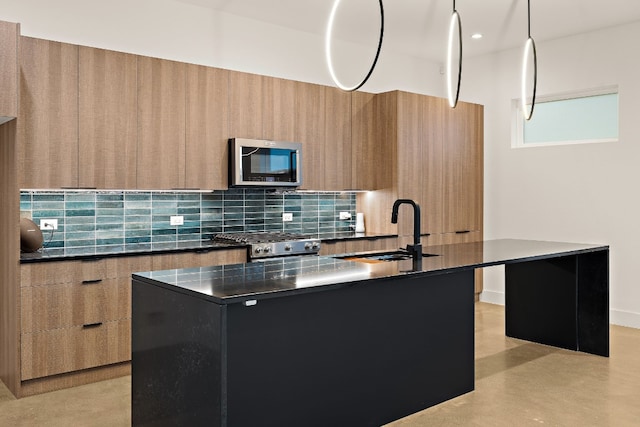 kitchen with sink, backsplash, pendant lighting, a kitchen island with sink, and appliances with stainless steel finishes