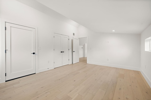 unfurnished bedroom featuring light wood-type flooring and multiple closets