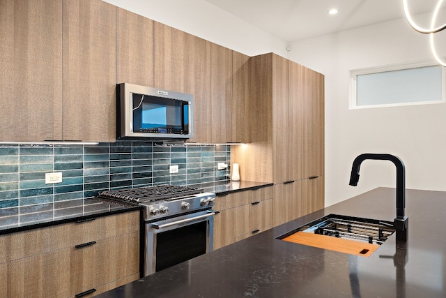 kitchen featuring sink, backsplash, appliances with stainless steel finishes, and dark stone counters