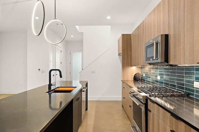 kitchen with pendant lighting, sink, decorative backsplash, dark stone countertops, and appliances with stainless steel finishes