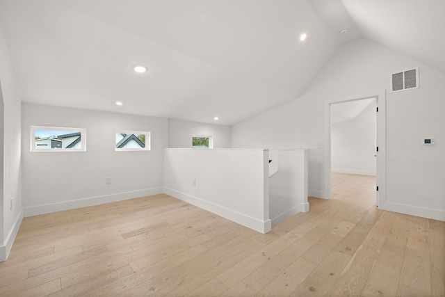 unfurnished room with lofted ceiling and light wood-type flooring