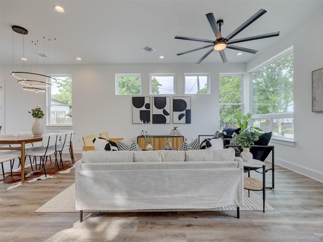 living room with ceiling fan with notable chandelier and light wood-type flooring