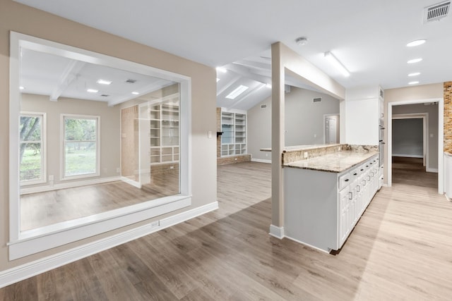 kitchen featuring vaulted ceiling with beams, light hardwood / wood-style flooring, white cabinets, and stone countertops