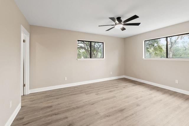 empty room with ceiling fan, a healthy amount of sunlight, and light hardwood / wood-style floors