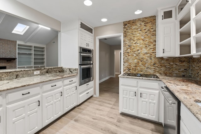 kitchen with a skylight, white cabinets, and appliances with stainless steel finishes