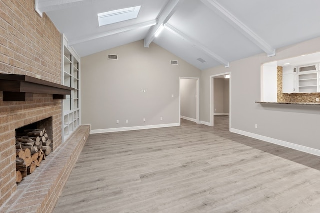 unfurnished living room with a fireplace, light hardwood / wood-style flooring, and vaulted ceiling with skylight