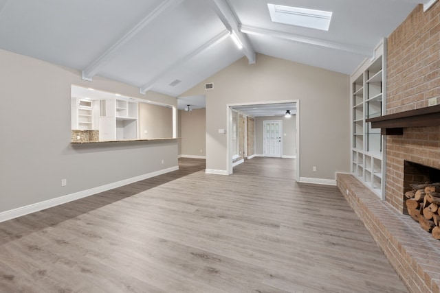 unfurnished living room with hardwood / wood-style flooring, lofted ceiling with skylight, and a fireplace